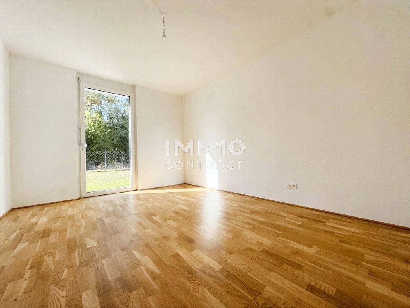 Ruhiges Schlafzimmer mit Parkettboden und direktem Zugang zum privaten Gartenbereich.