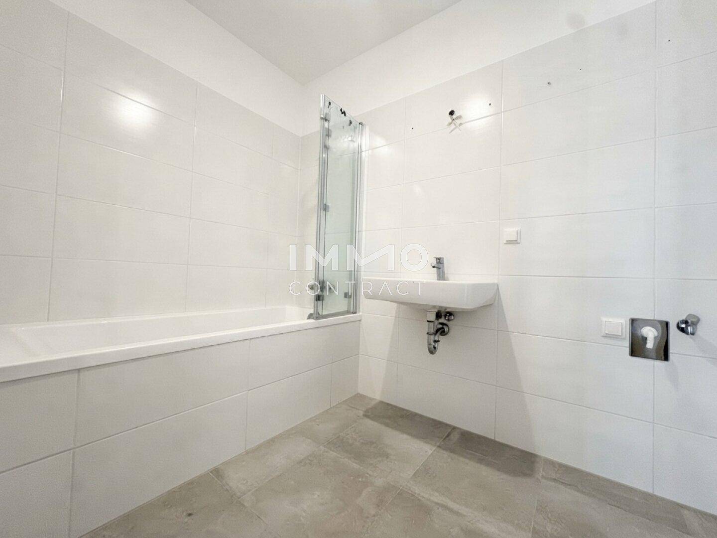 Modernes Badezimmer mit Badewanne, Duschabtrennung und weiß gefliesten Wänden.