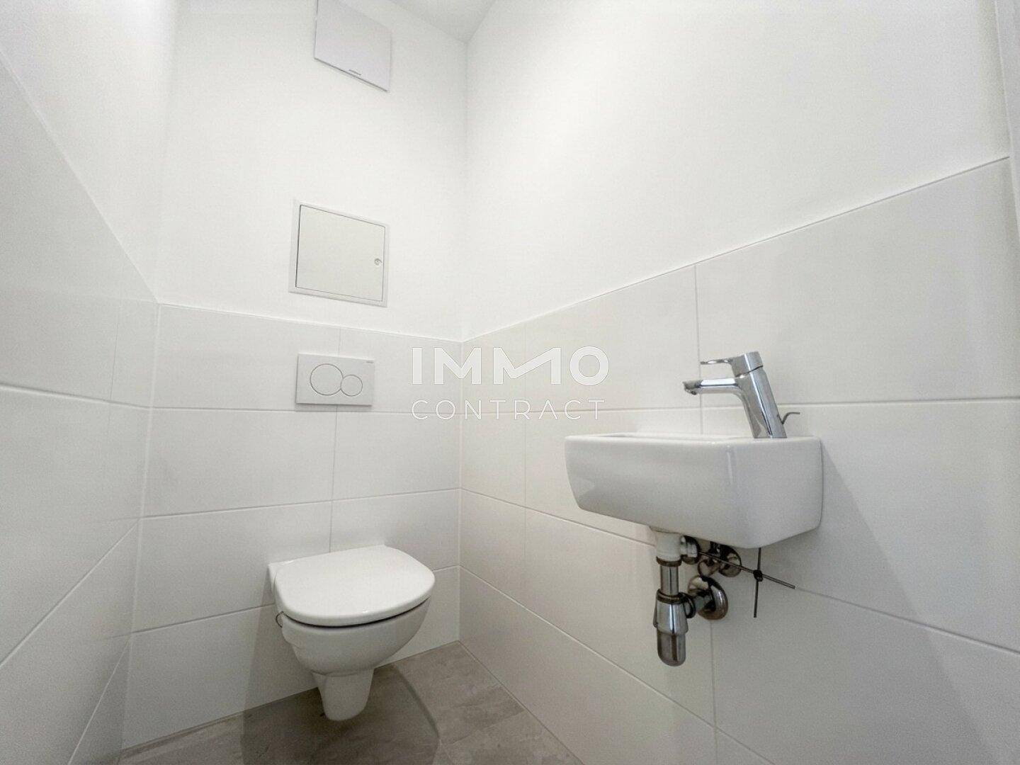 Separates Gäste-WC mit wandhängender Toilette und kleinem Handwaschbecken.