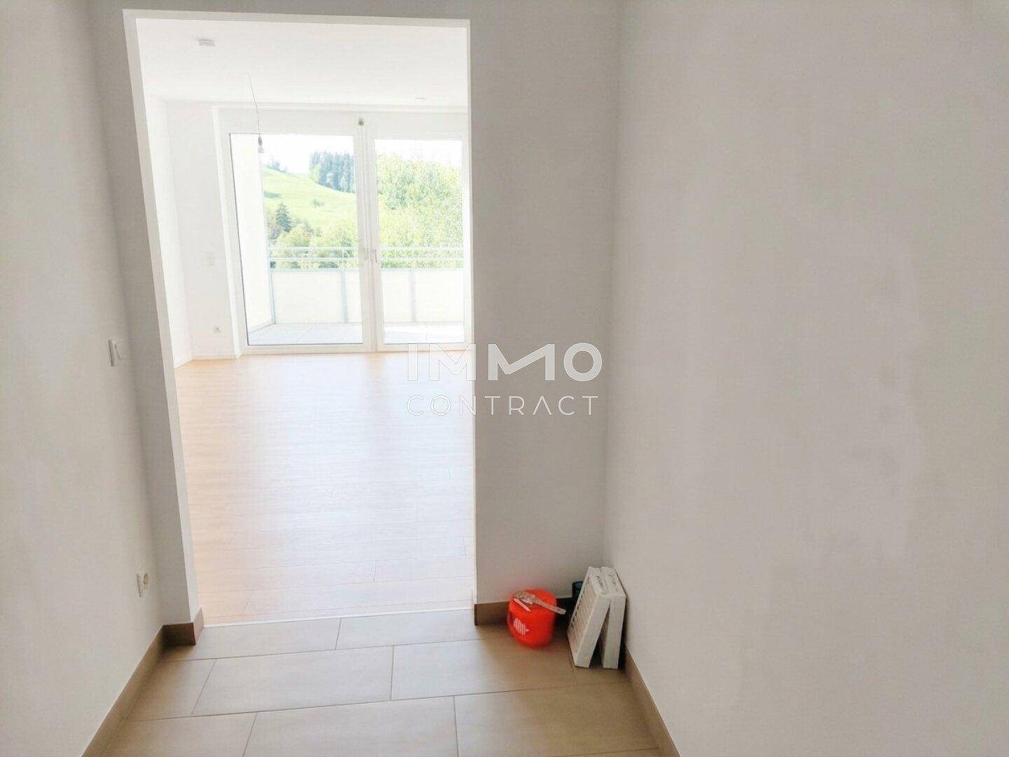 Heller Eingangsbereich mit Fliesenboden, der zu einem Wohnzimmer mit Balkonzugang führt.