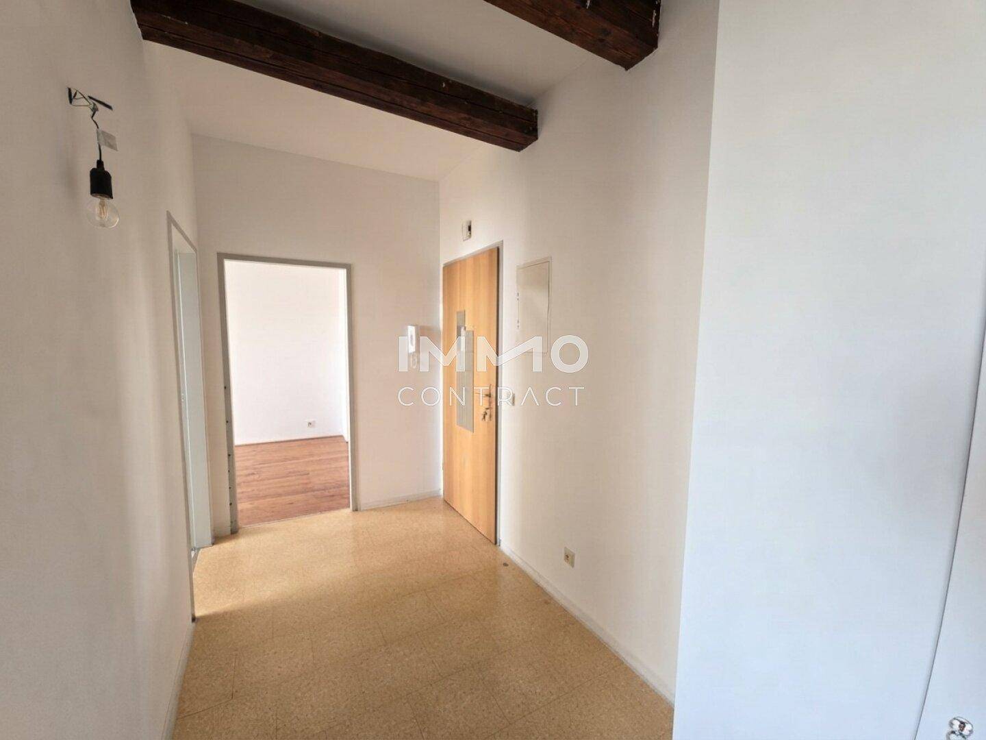 Heller Flur mit sichtbaren Holzbalken und Zugang zu weiteren Räumen.