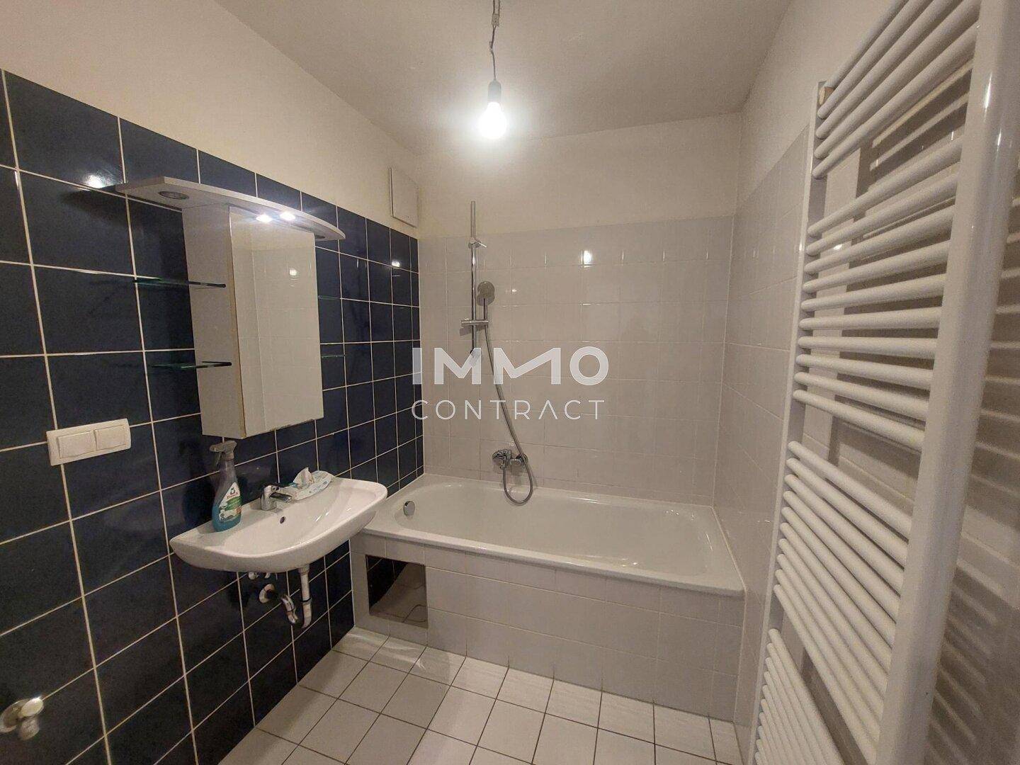 Badezimmer mit Badewanne, Waschbecken, Spiegelschrank und Handtuchheizkörper.