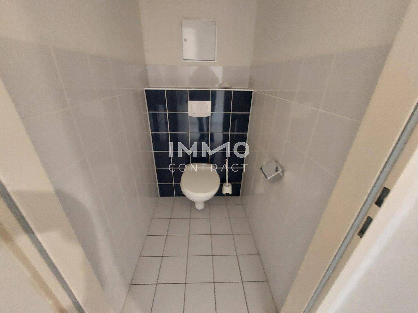 Separate Toilette mit WC und Fliesenboden.