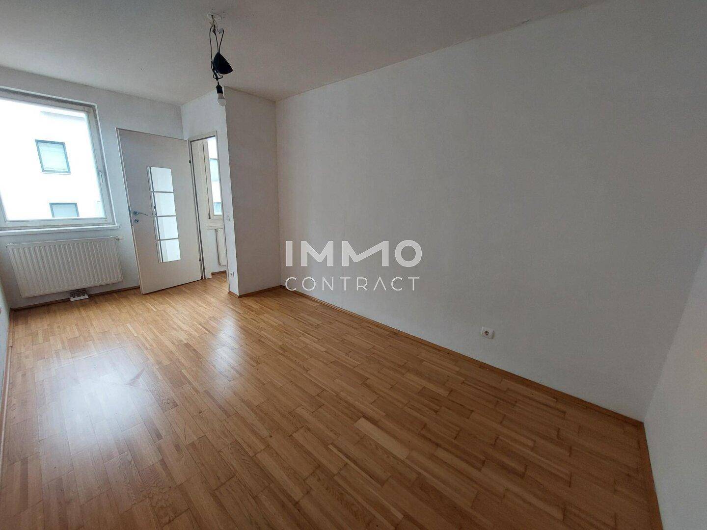 Helles Schlafzimmer mit Parkettboden und Fenster.