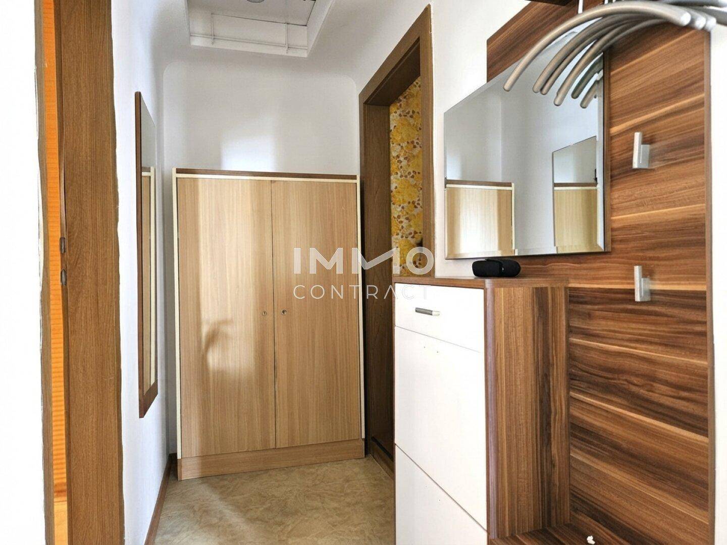 Heller Flur mit Holzmöbeln, Spiegel und Garderobe, einladender Eingangsbereich.