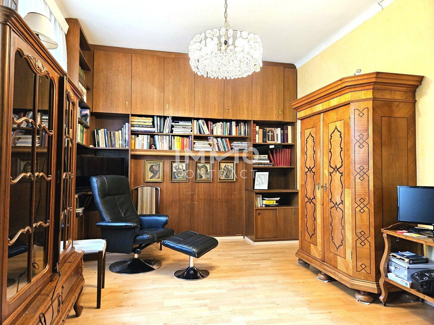 Gemütliches Wohnzimmer mit umfangreichen Holzregalen, Parkettboden und Kronleuchter.