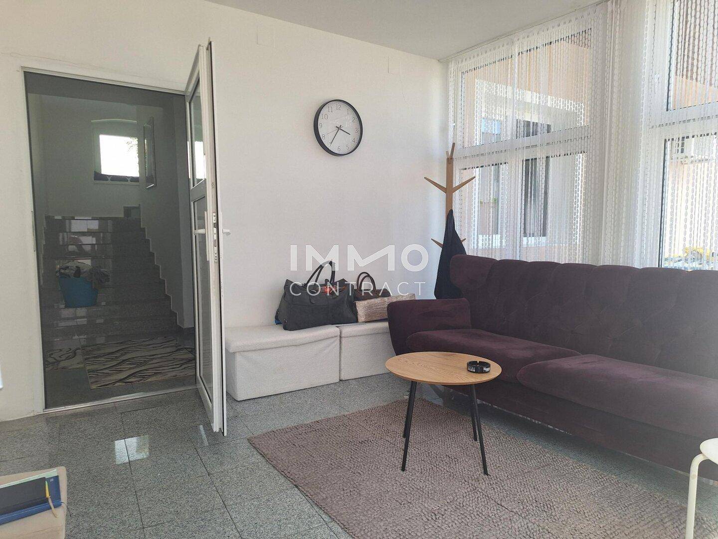 Gemütlicher Wohnbereich mit Sofa, Couchtisch und Blick auf die Treppe im Hintergrund.
