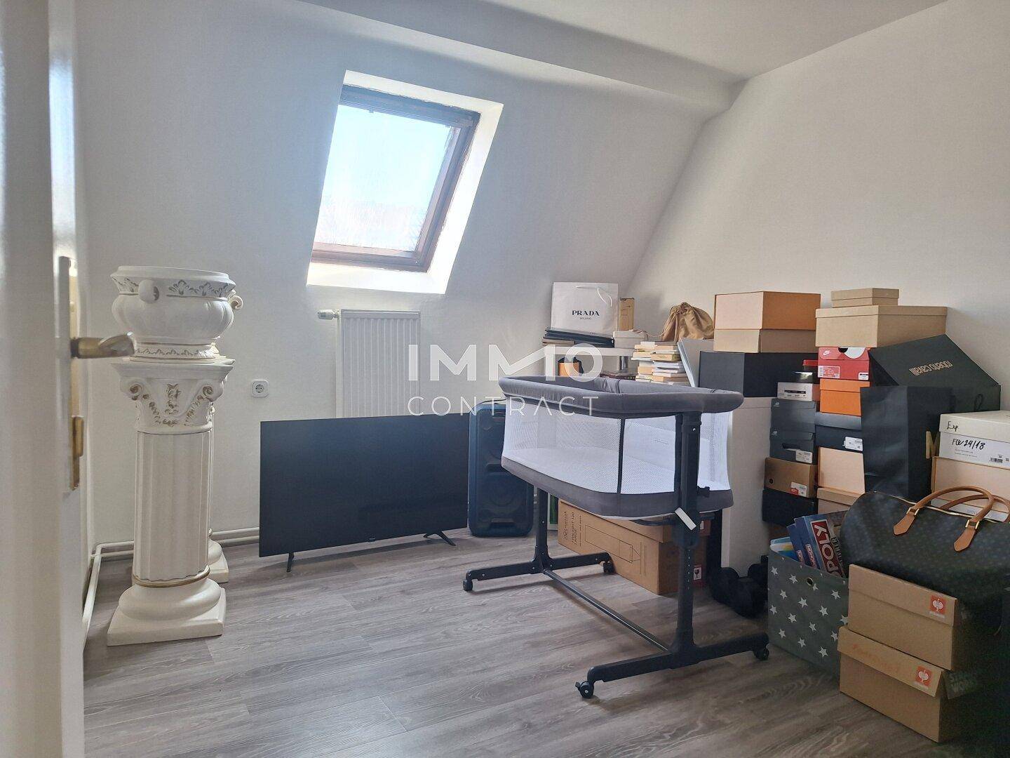 Dachgeschosszimmer mit Schrägen, Laminatboden und Dachfenster für natürliches Licht.