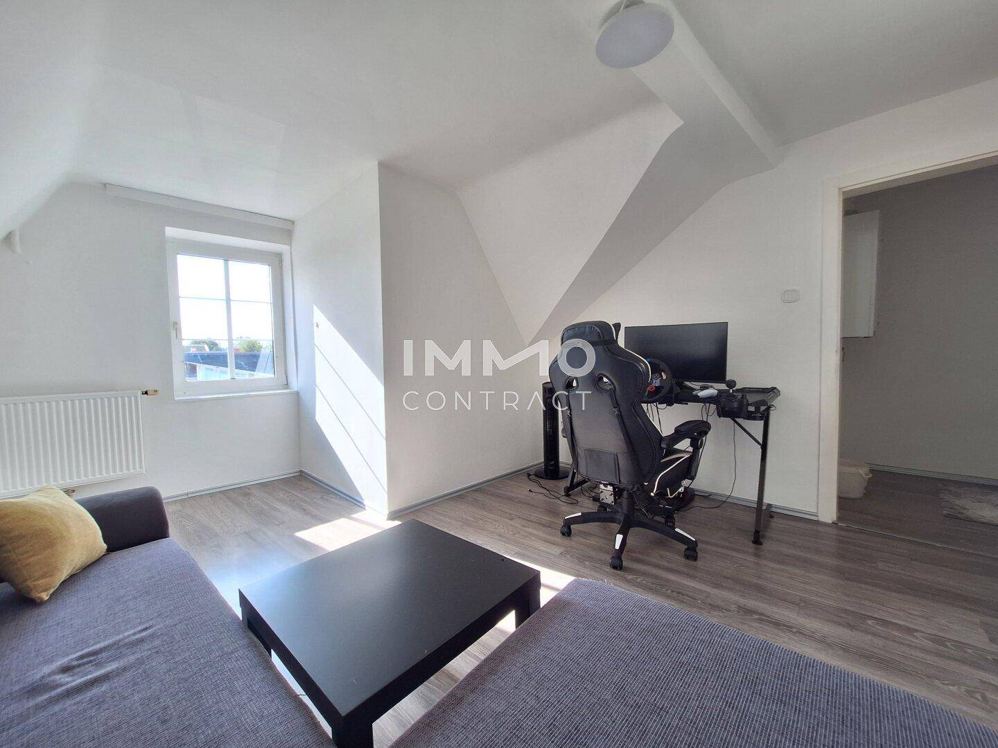 Dachgeschosszimmer als Büro eingerichtet mit Laminatboden und Schreibtisch.