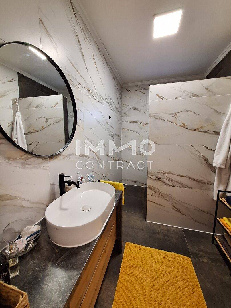 Modernes Badezimmer mit Marmorfliesen, ovalem Waschbecken und begehbarer Dusche.