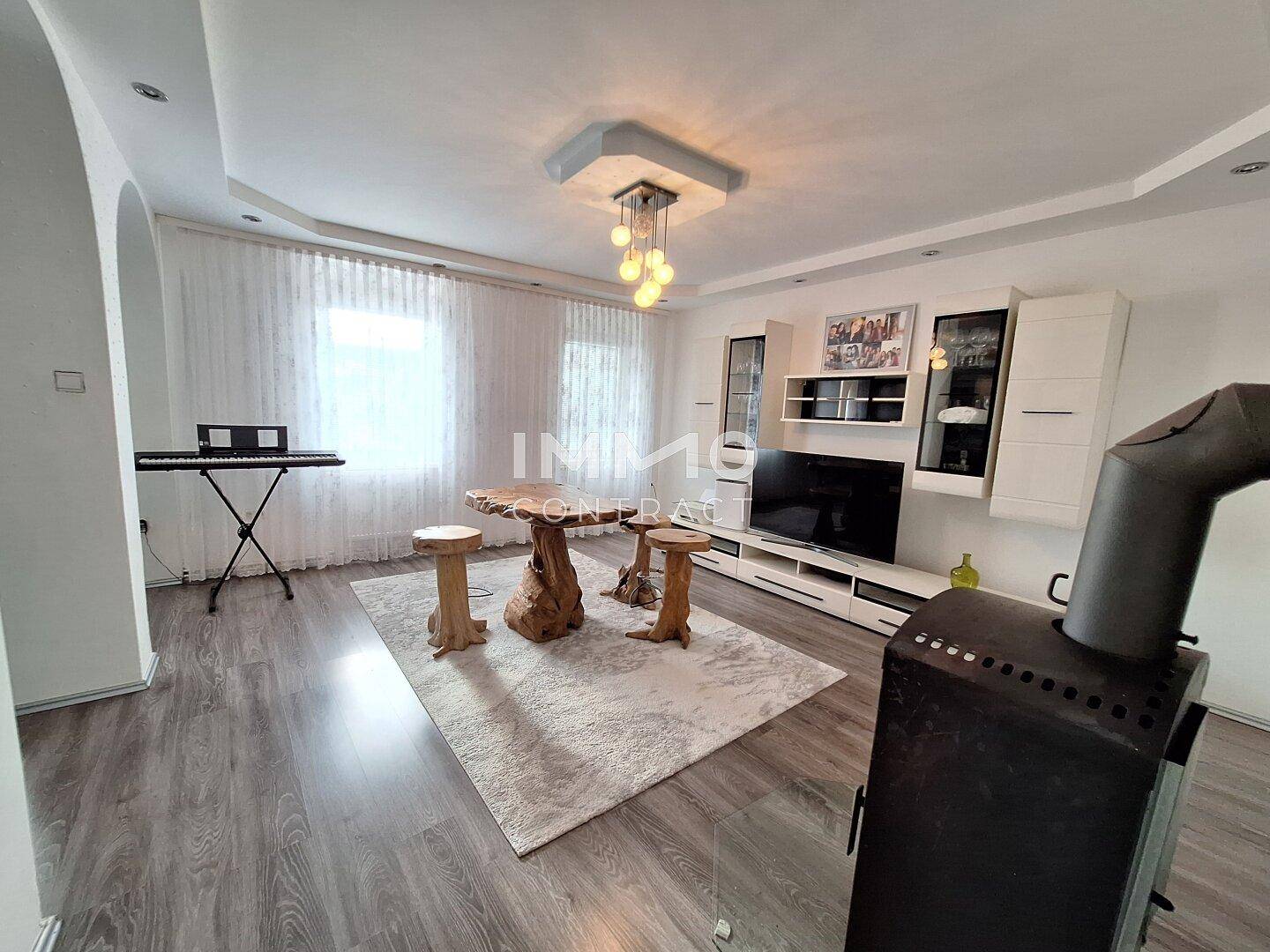 Wohnzimmer mit Holzboden, Kaminofen, TV-Möbeln und einem dekorativen Tisch.