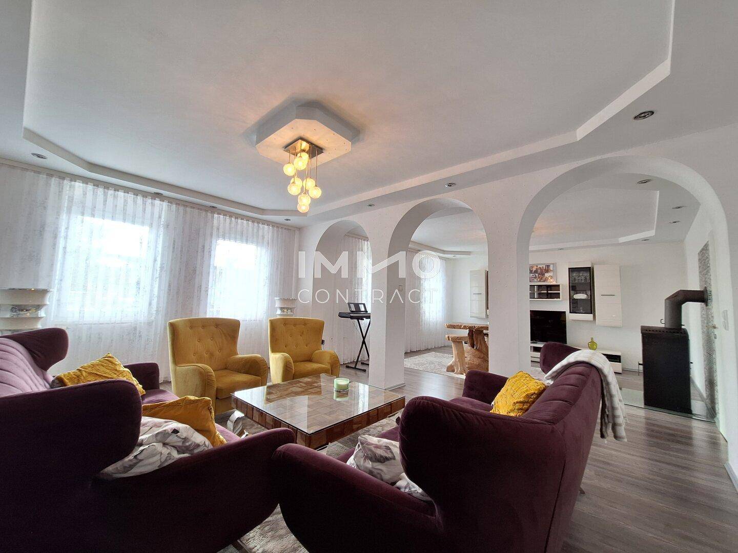 Heller Wohnbereich mit bequemen Sofas, gelben Sesseln und Holzboden.
