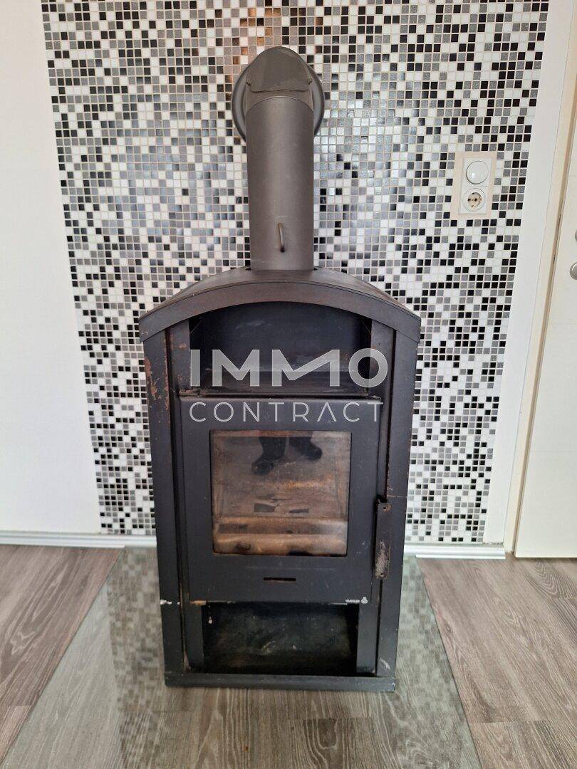 Moderner Kaminofen vor einer Wand mit Mosaikfliesen im Wohnbereich.