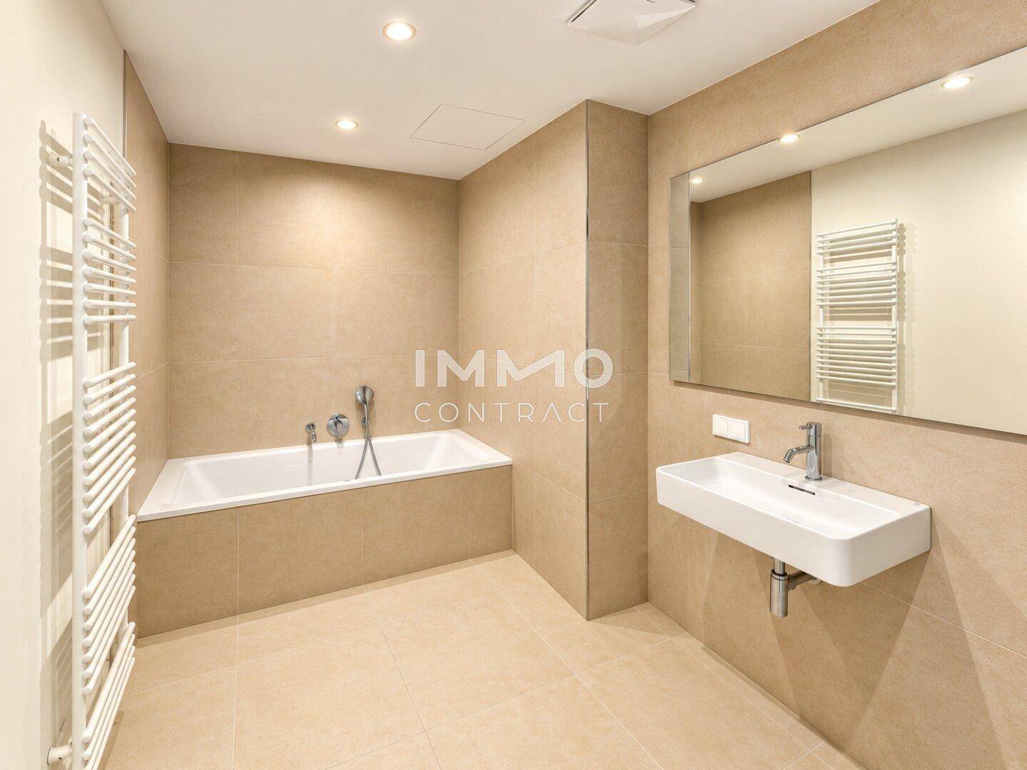 Modernes Badezimmer mit beigefarbenen Fliesen, Badewanne und wandhängendem Waschbecken.