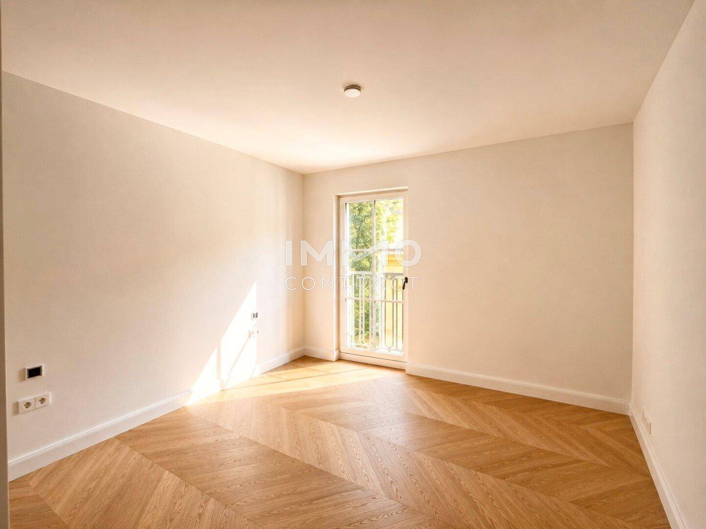Ruhiges Zimmer mit Fischgrätparkett und einem Fenster, das viel natürliches Licht hereinlässt.