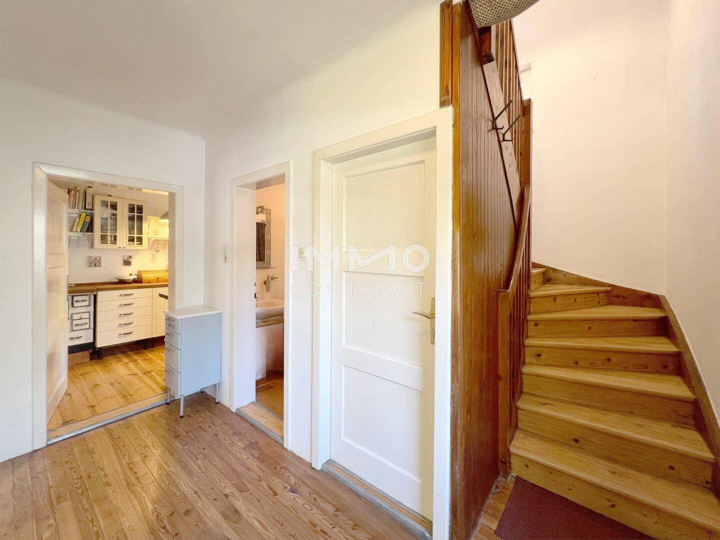 Heller Flur mit Holztreppe, der Zugang zur Küche und einem Badezimmer bietet.