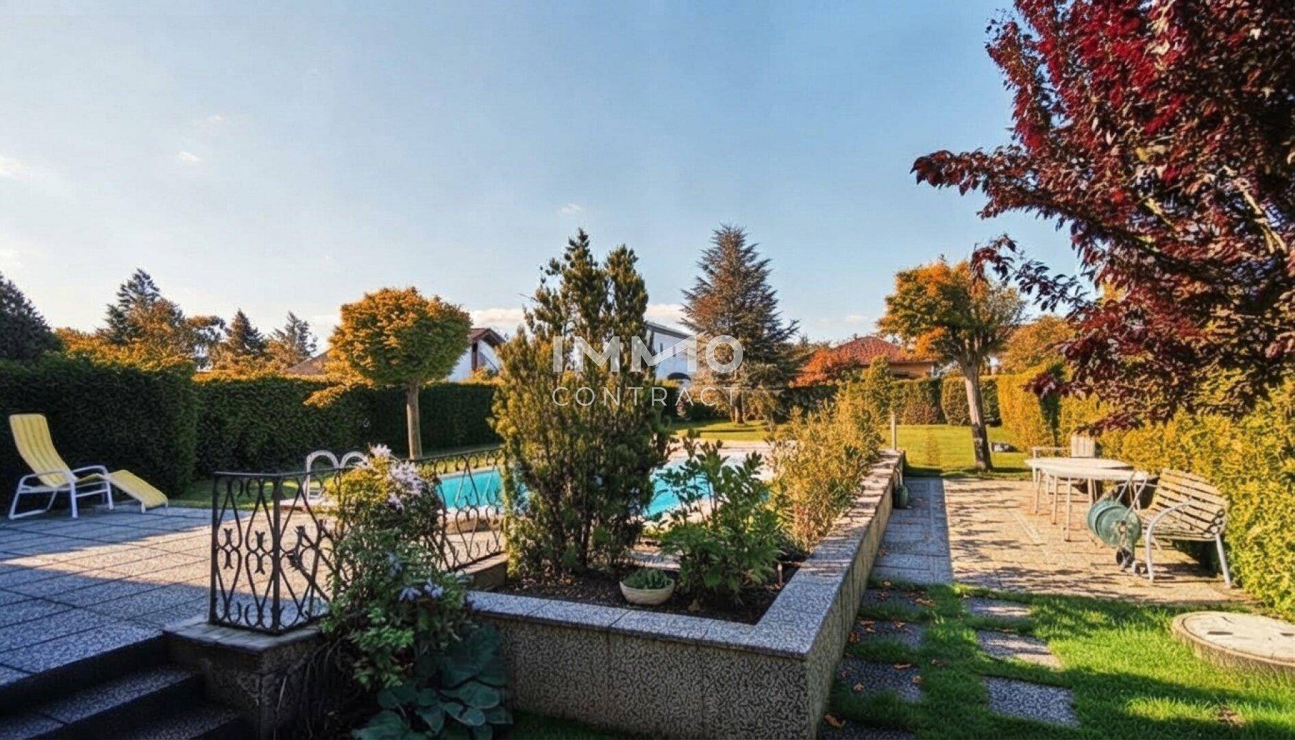 Gepflegter Garten mit Pool, Essbereich im Freien und üppiger Bepflanzung.