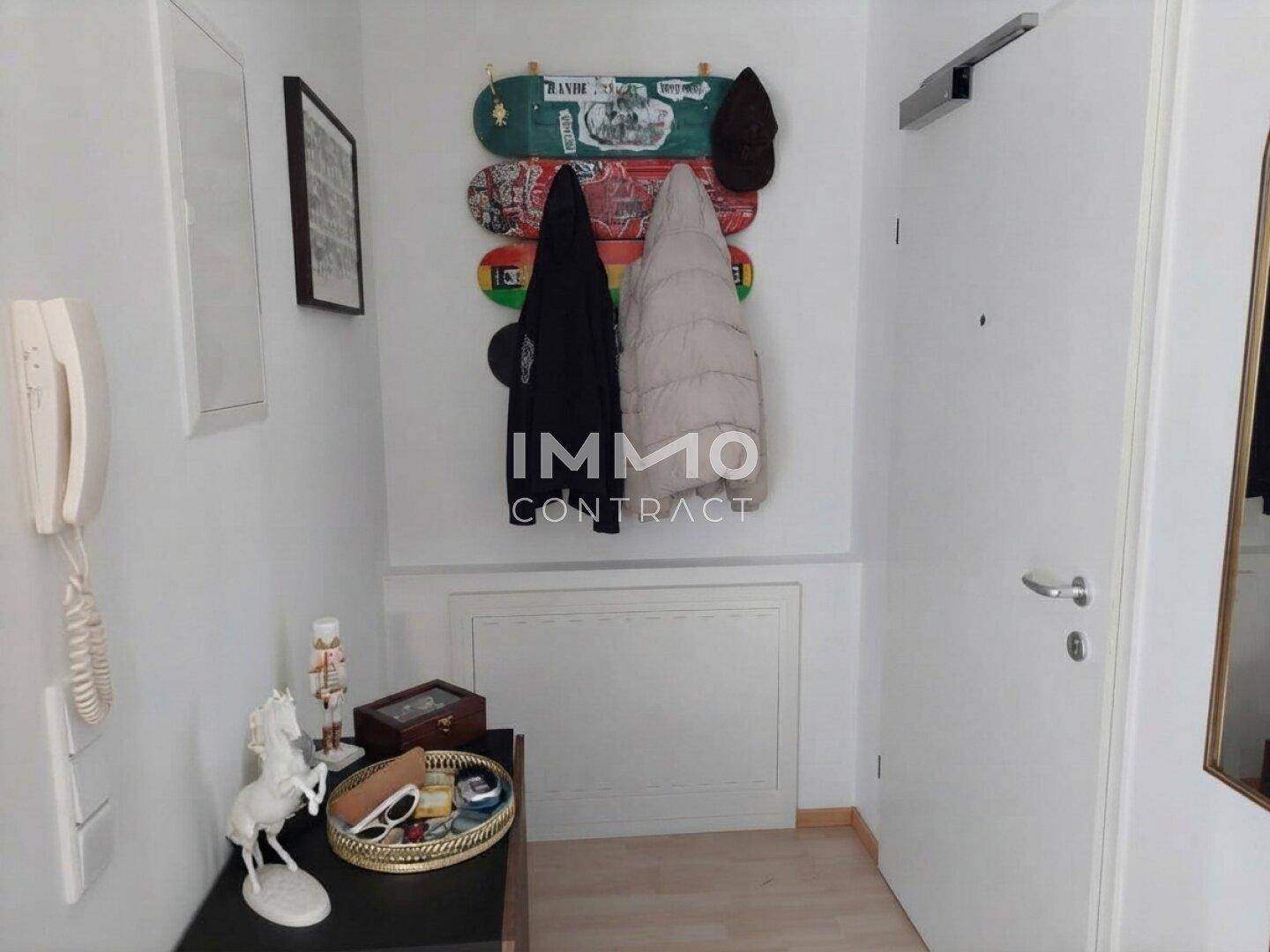Eingangsbereich mit Garderobe, Gegensprechanlage und einem kleinen Beistelltisch.