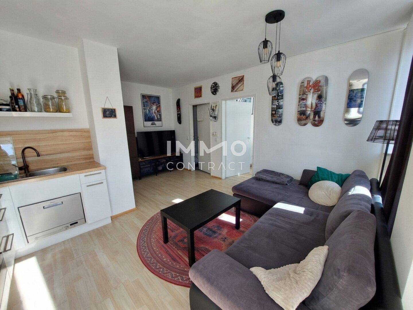 Wohnzimmer mit großem Ecksofa, Couchtisch und offener Verbindung zur Küchenzeile.