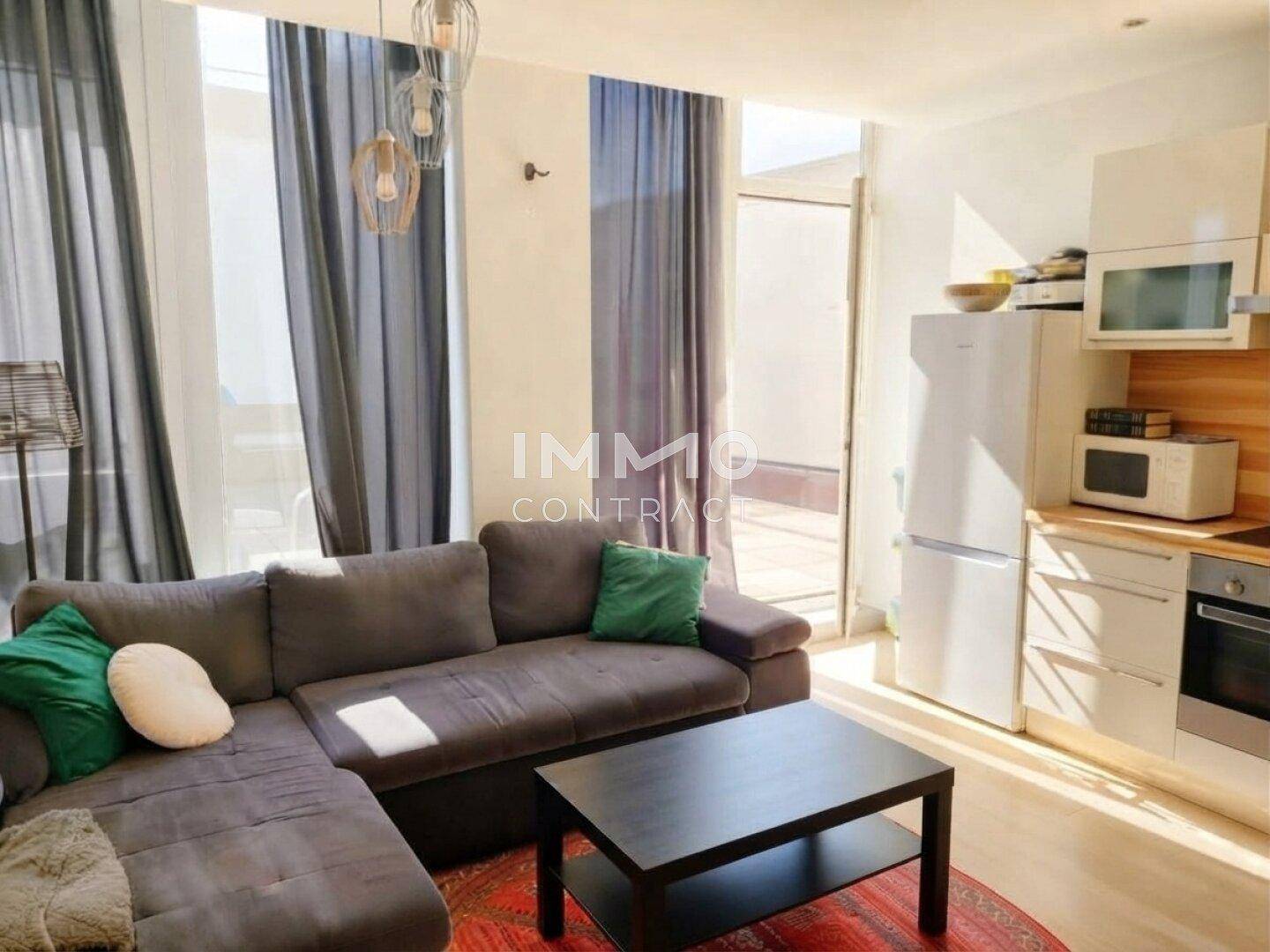 Heller Wohnbereich mit Sofa, Küchenzeile und direktem Zugang zur Außenterrasse.