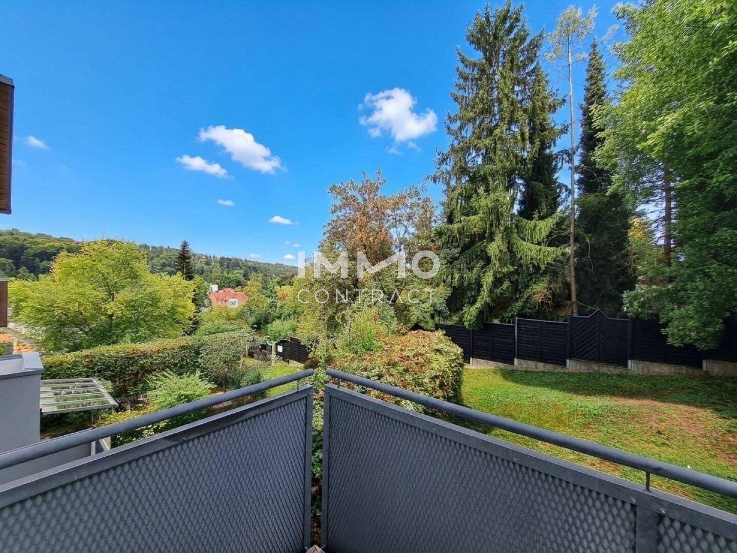 Panoramablick von einem Balkon auf eine grüne Hügellandschaft mit Bäumen und Häusern.