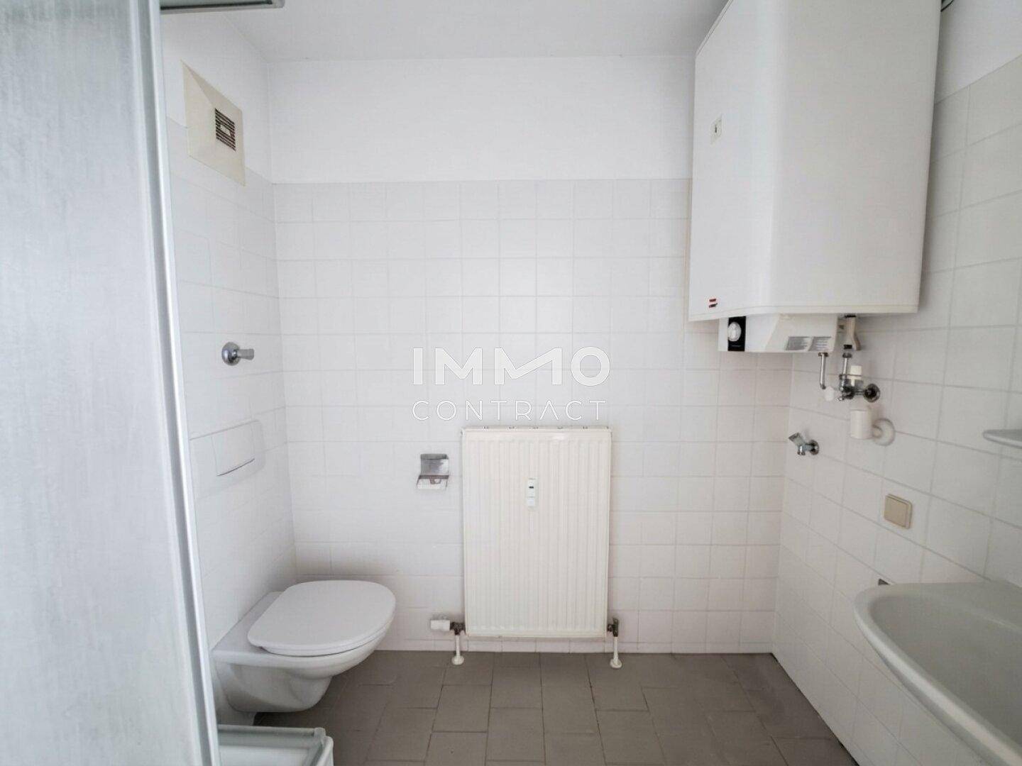 Gefliestes Badezimmer mit Toilette, Heizkörper und Warmwasserboiler, inklusive Badewanne.