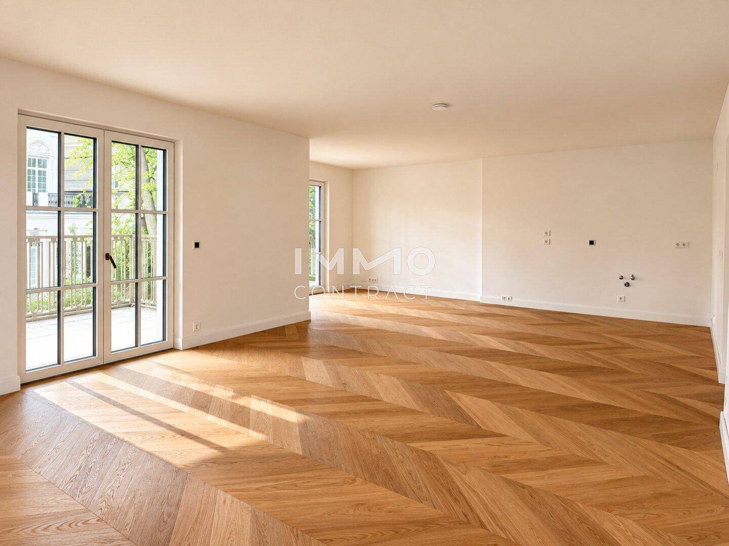 Lichtdurchfluteter Raum mit modernem Fischgrätparkett und Zugang zu einem französischen Balkon.