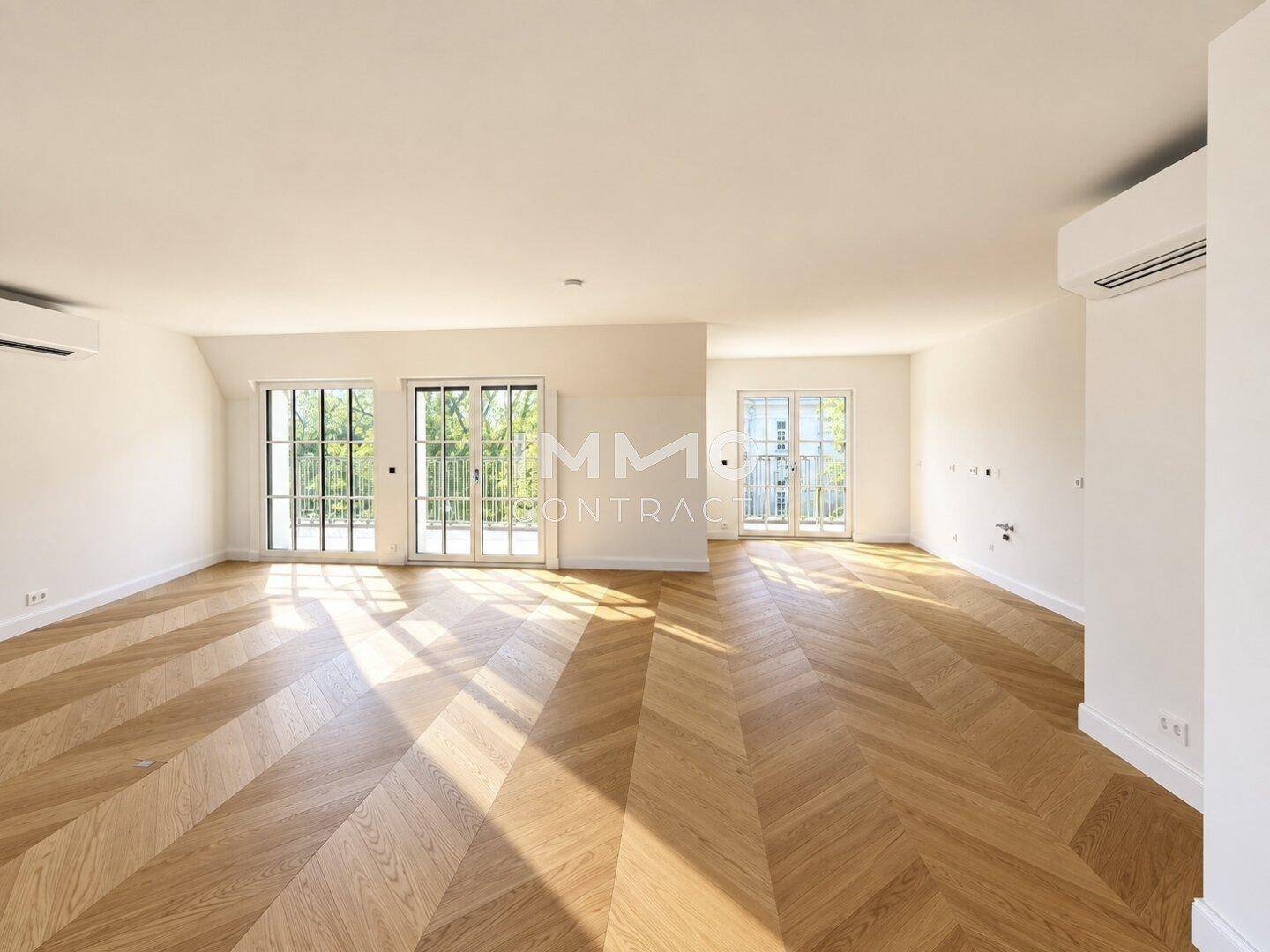 Heller Wohnraum mit Fischgrätparkett und mehreren Fenstertüren für viel Licht.
