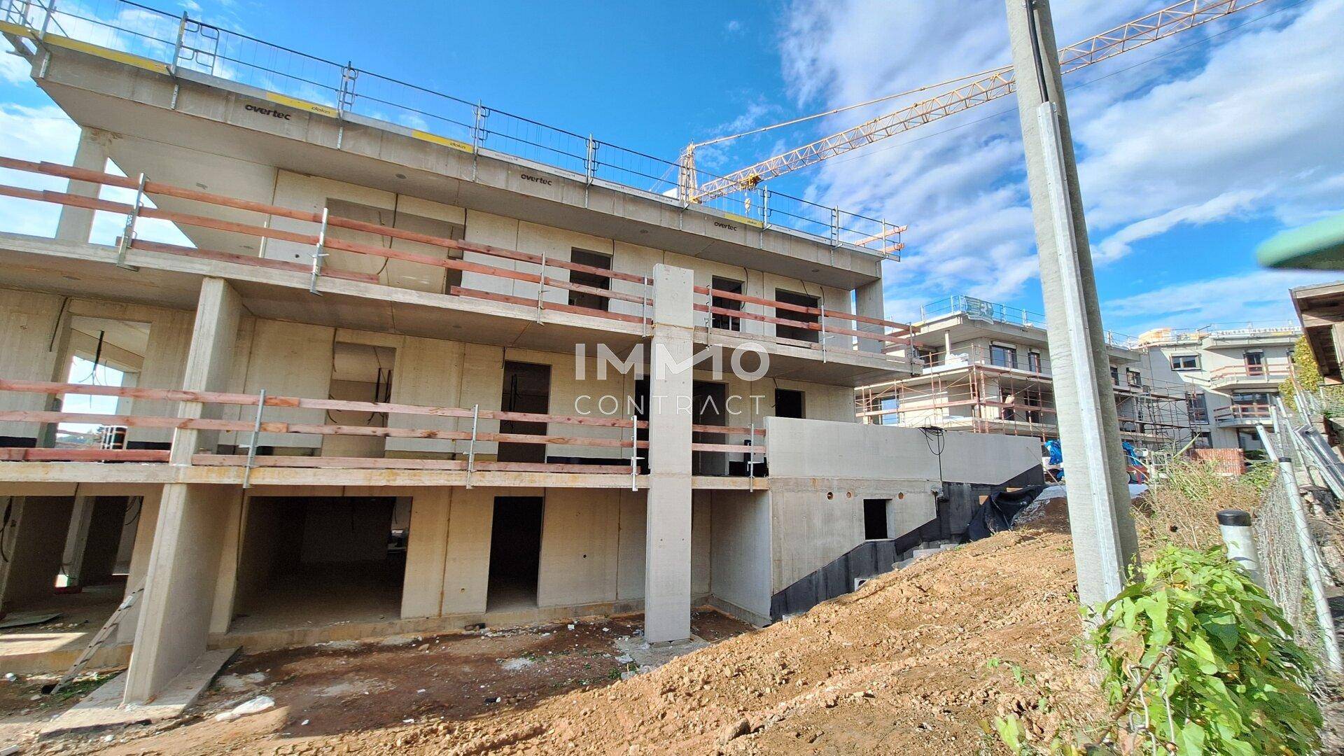 Blick auf die Baustelle des Neubaus mit angrenzenden Gebäuden und einem Baukran im Hintergrund.