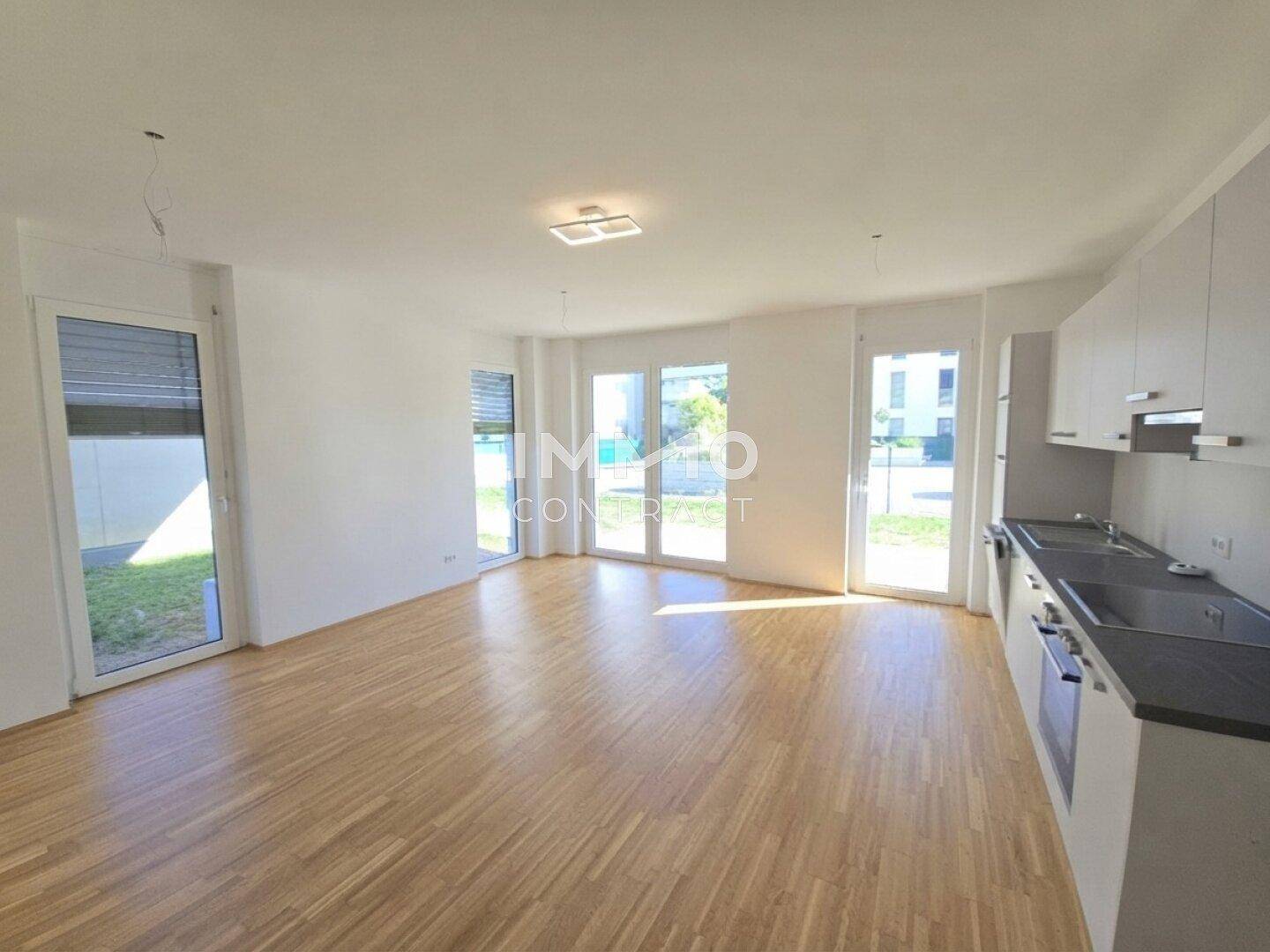 Heller Wohn- und Essbereich mit Holzboden und Zugang zu Außenbereichen.