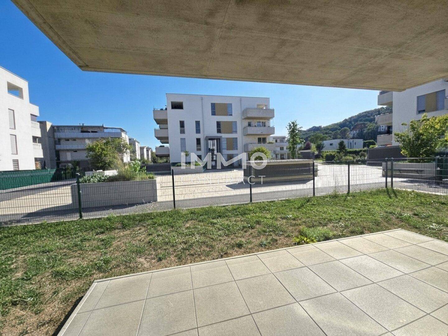 Geflieste Terrasse im Erdgeschoss mit Blick auf die umliegenden Gebäude und Grünflächen.