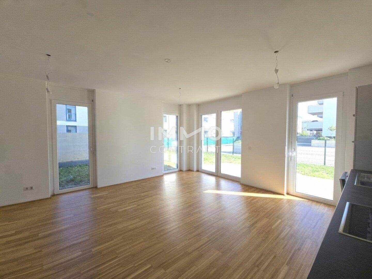 Heller Wohnbereich mit Parkettboden und offener Küche, ideal für modernes Wohnen.