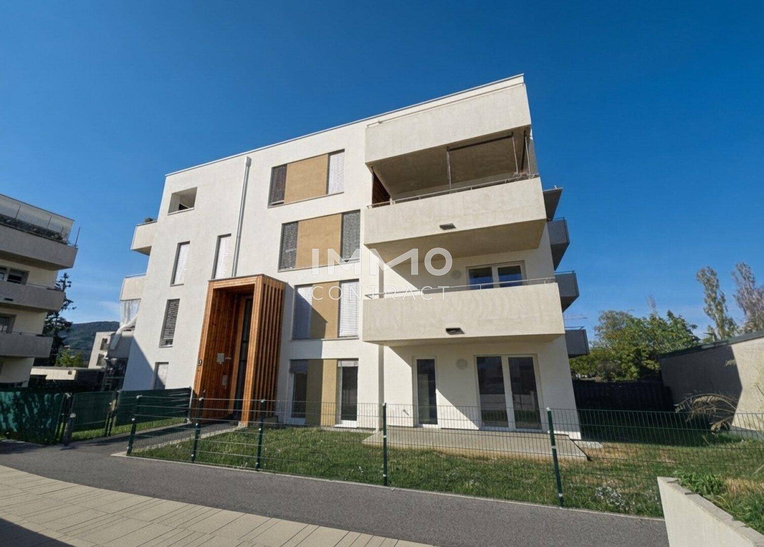 Moderne Architektur des Wohngebäudes mit Balkonen und Holzverkleidung an der Fassade.