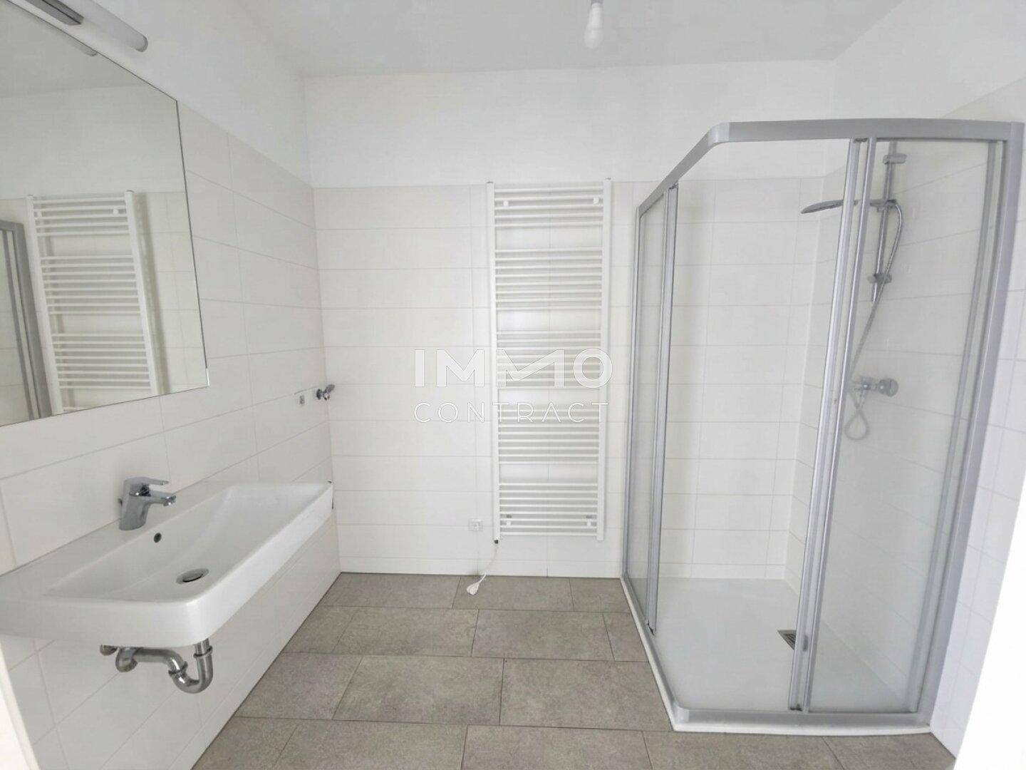 Modernes Badezimmer mit Duschkabine, Waschbecken und beheiztem Handtuchhalter.
