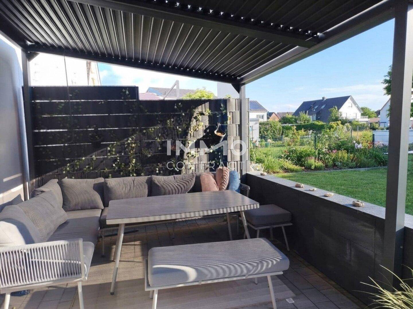 Überdachte Terrasse mit bequemen Gartenmöbeln und Blick in den Garten.