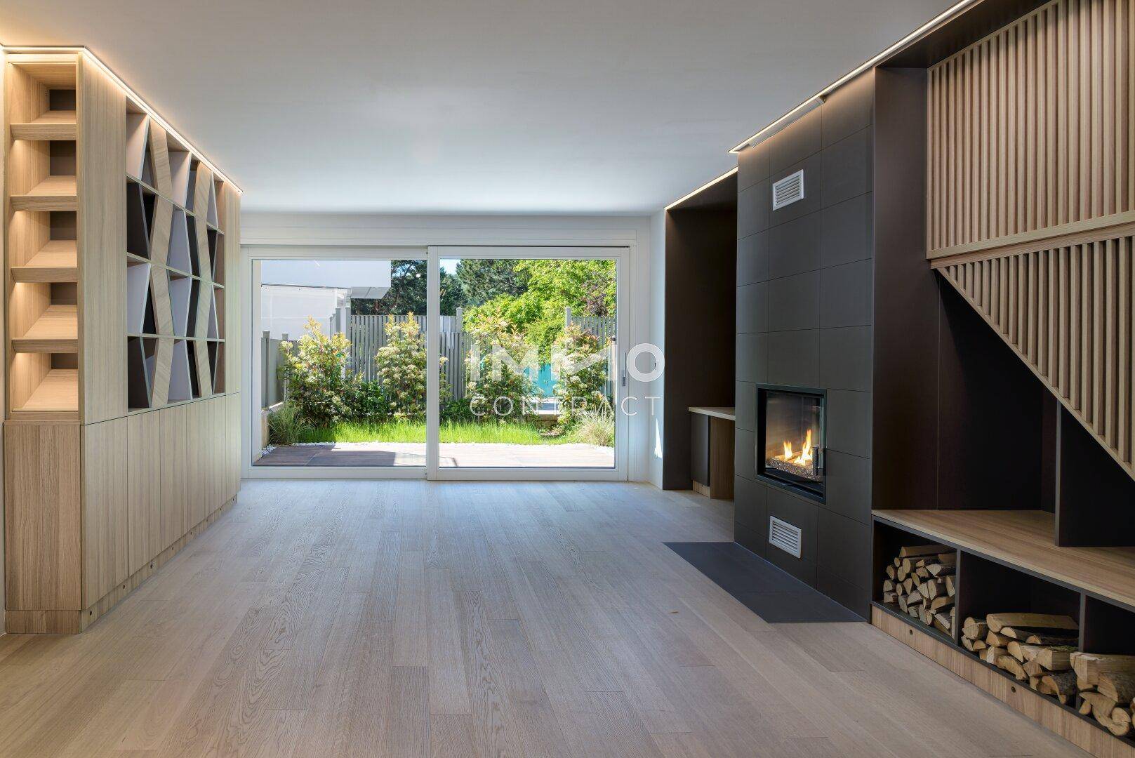 Geräumiges Wohnzimmer mit Kamin, Holzboden und großen Schiebetüren zum Garten.