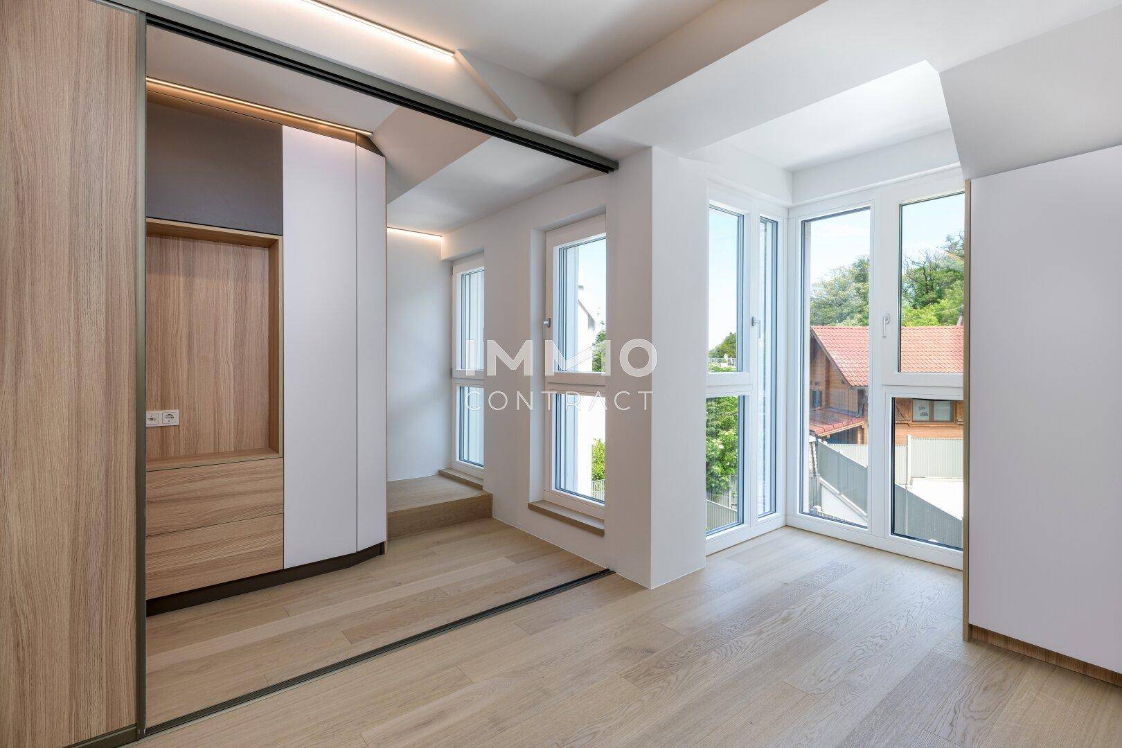 Heller Flur oder offener Bereich mit Holzboden, großen Fenstern und viel Tageslicht.
