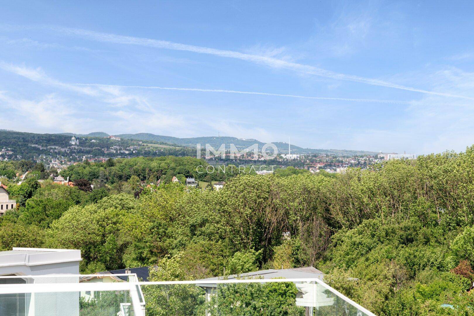 Panoramablick von der Dachterrasse über eine weite, grüne Landschaft und Siedlung.