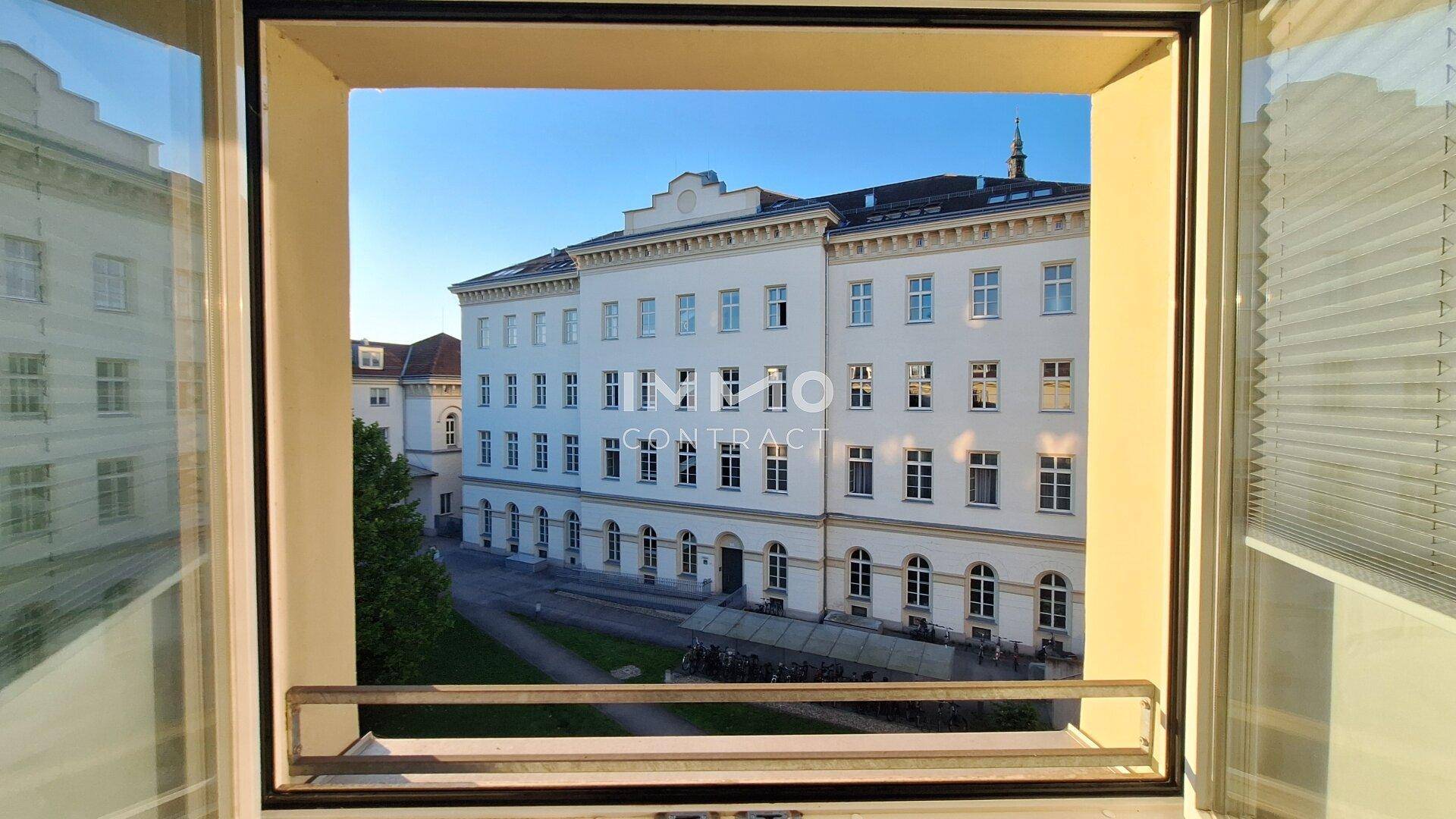Blick aus dem Fenster auf die klassische Fassade eines großen Wohngebäudes.