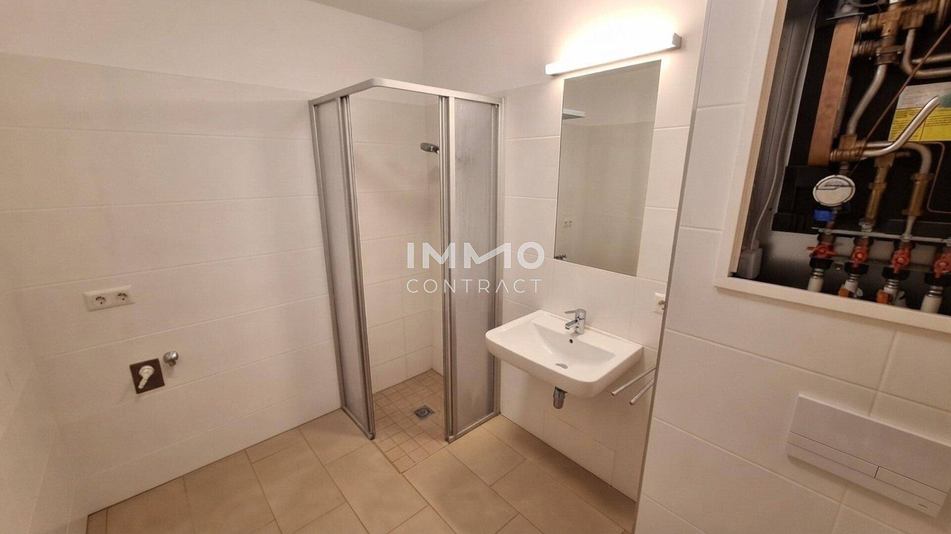 Funktionales Badezimmer mit Duschkabine, Waschbecken und Spiegel, hell gefliest.