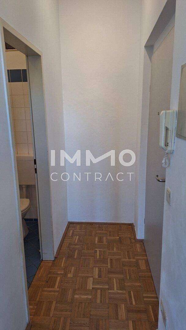 Schmaler Flur mit Parkettboden und Zugang zu angrenzenden Räumen, inklusive Badezimmer.