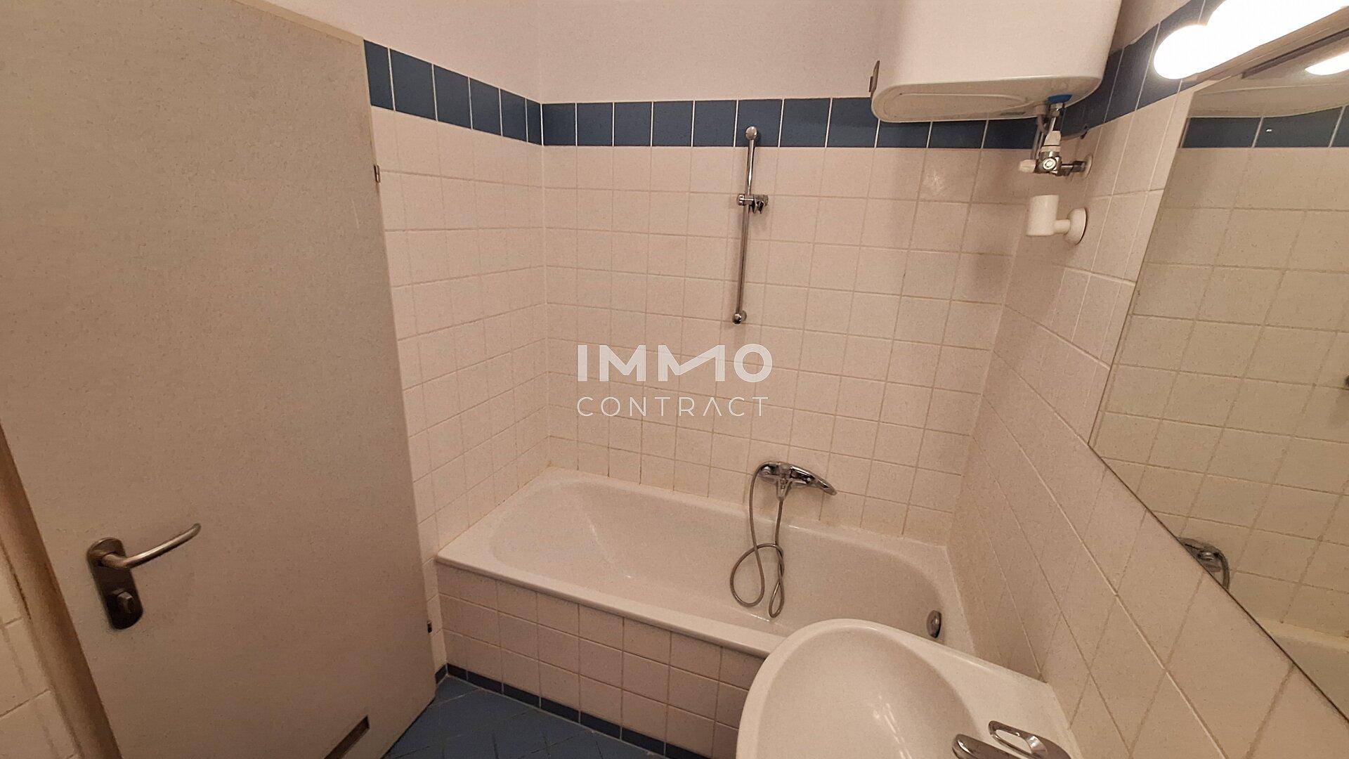 Badezimmer mit Badewanne, Waschbecken und weiß-blauen Fliesen, praktisch gestaltet.