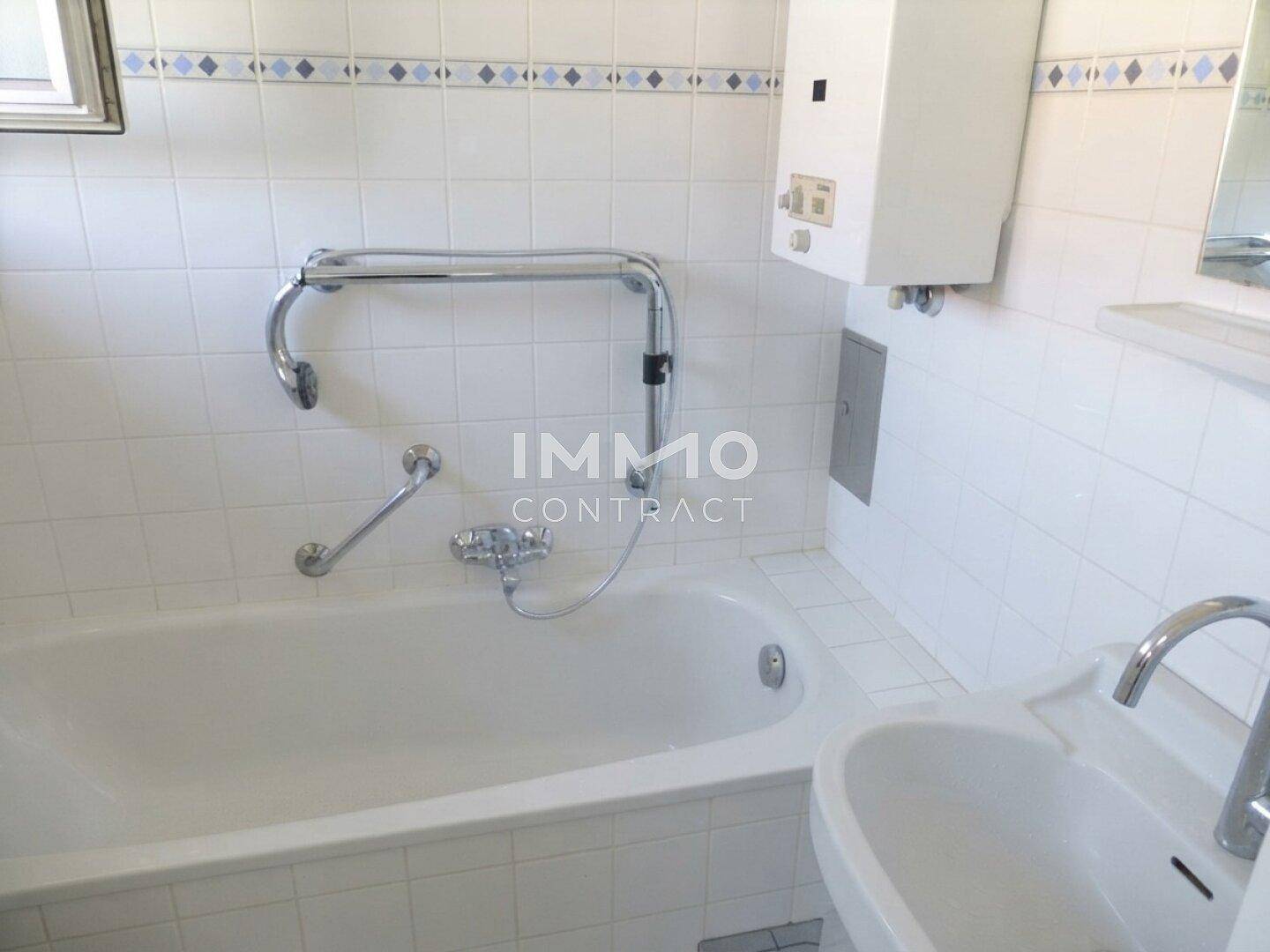 Funktionales Badezimmer mit Badewanne, Waschbecken und Haltegriffen für zusätzliche Sicherheit.