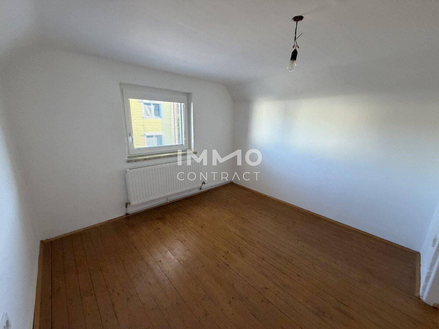 Helles Zimmer mit Holzdielenboden und schrägen Wänden, typisch für ein Dachgeschoss.
