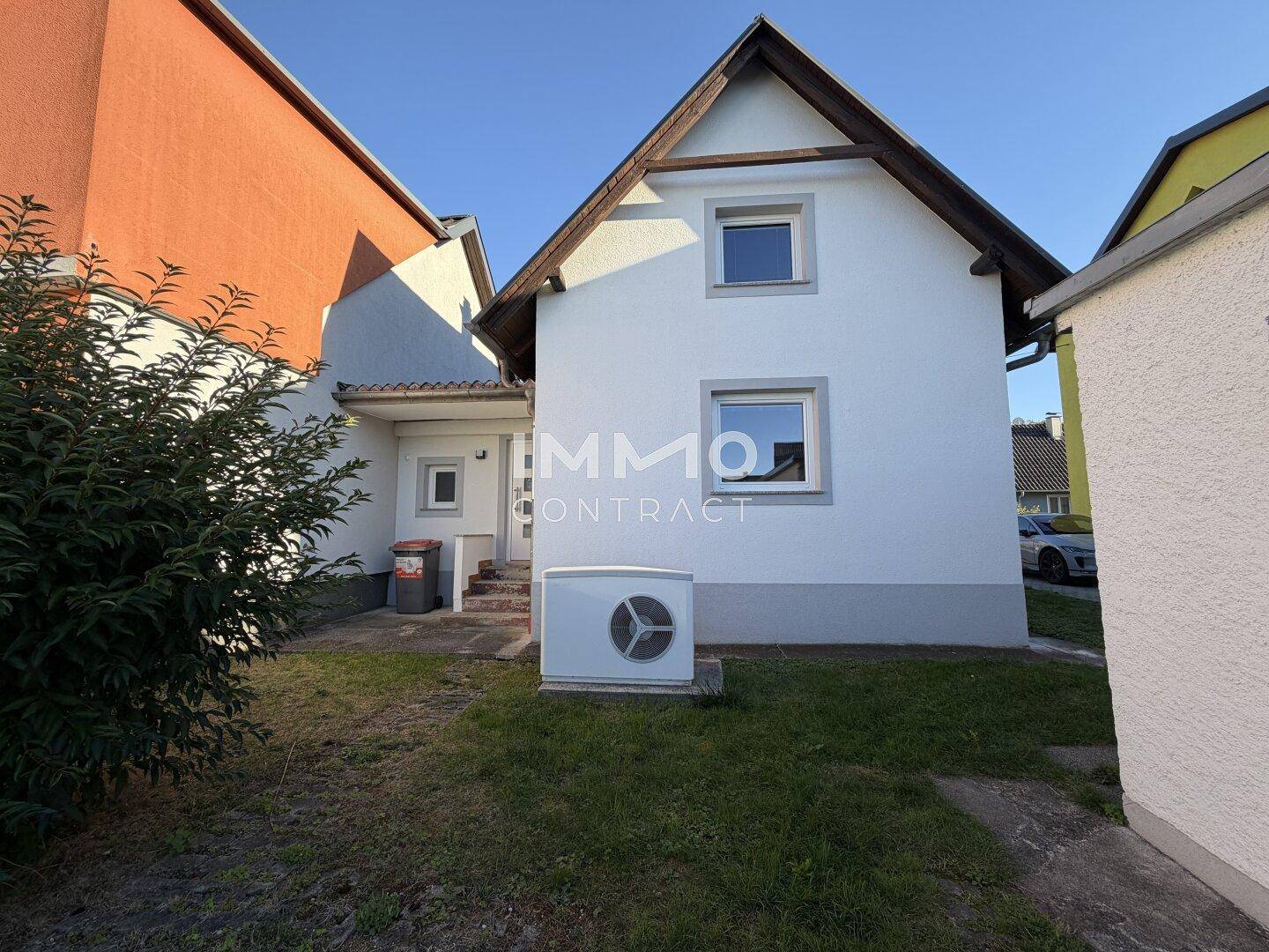 Rückseite des Hauses mit Wärmepumpe und Zugang zum Gartenbereich.