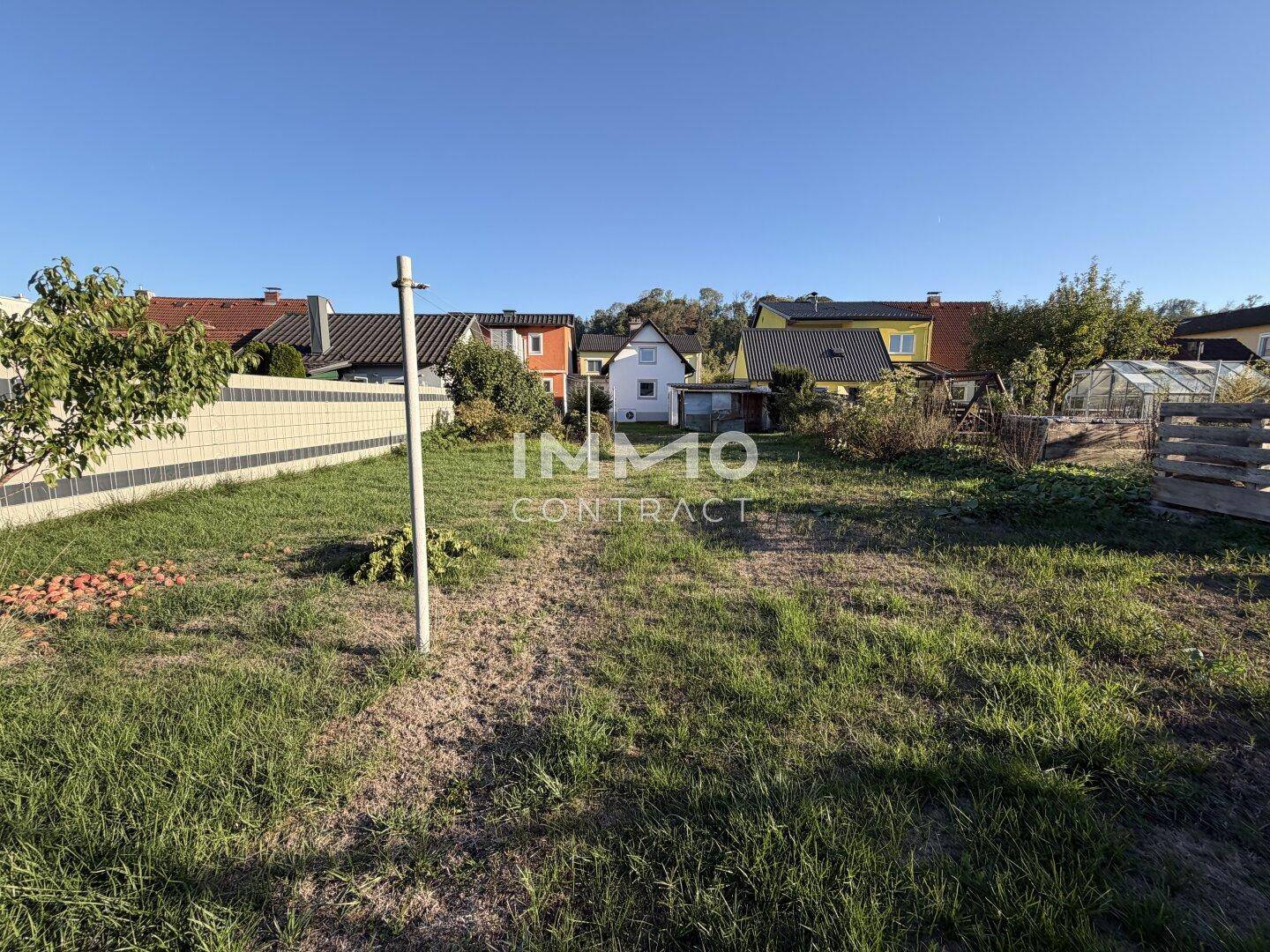 Große, sonnige Gartenfläche mit Rasen und Blick auf die umliegenden Häuser.