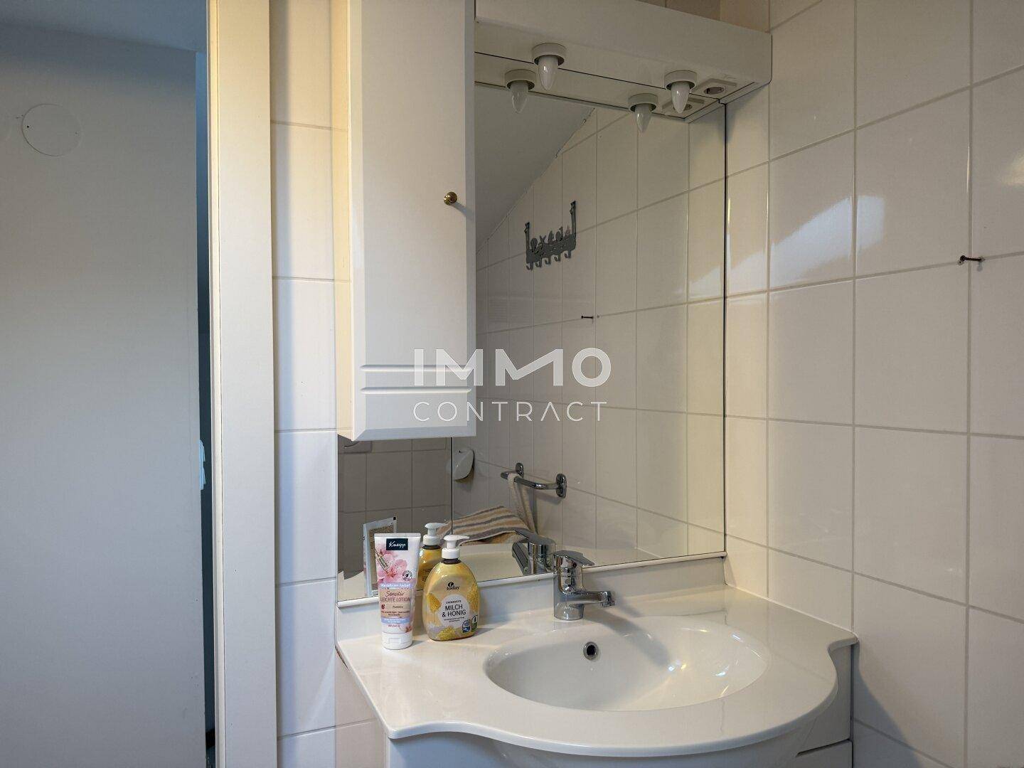 Waschbecken mit Spiegelschrank und weißen Fliesen im Badezimmer.