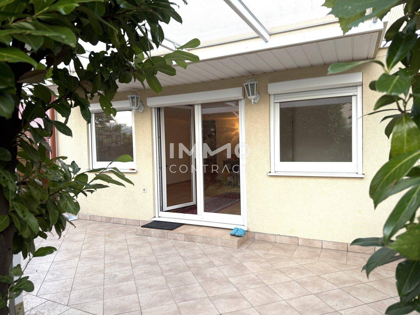 Geflieste Terrasse mit Überdachung und Zugang zum Innenbereich des Hauses.