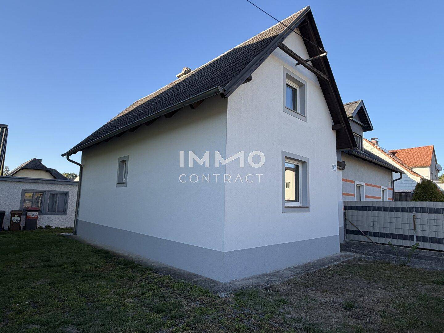 Seitenansicht des weißen Einfamilienhauses mit schlichten Fenstern und Satteldach.