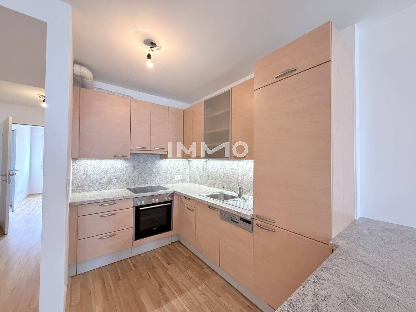 Moderne Küche mit hellen Holzfronten, Granit-Arbeitsplatte und integrierten Geräten.